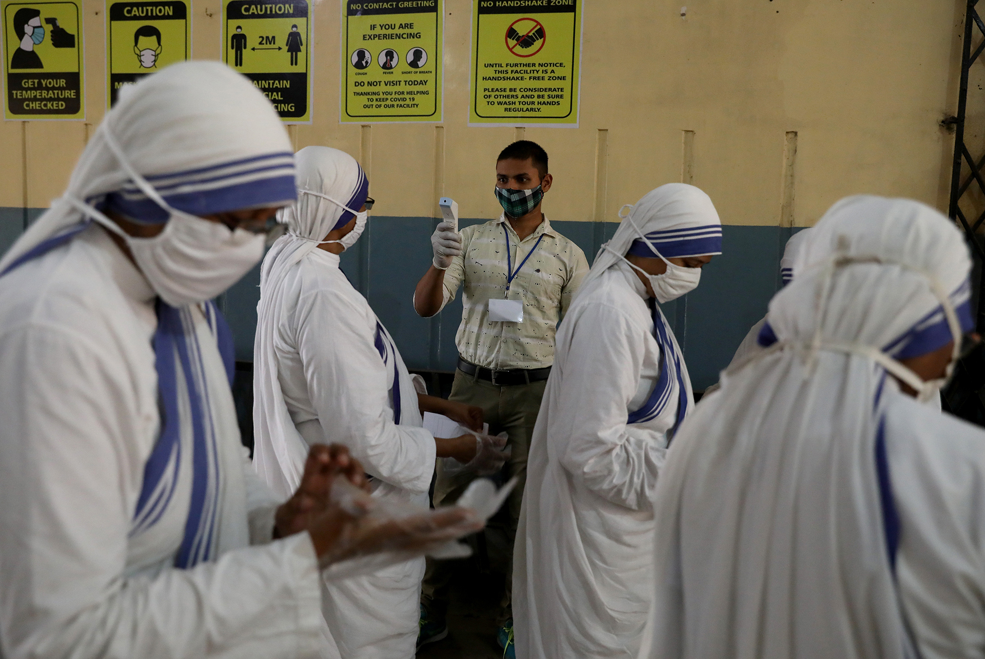 An election official checks the temperature of Catholic nuns from the Missionaries of Charity before they cast their vote at a polling station in Kolkata