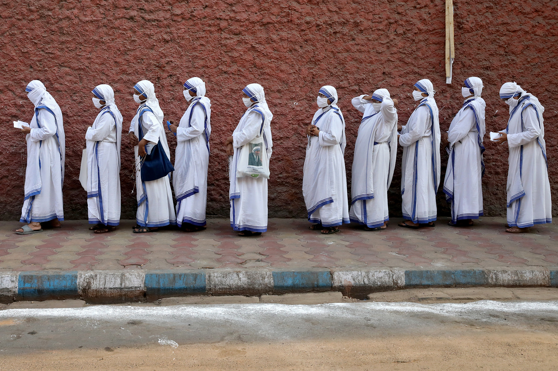 Catholic nuns from the Missionaries of Charity wait in line to cast their vote at a polling station in Kolkata