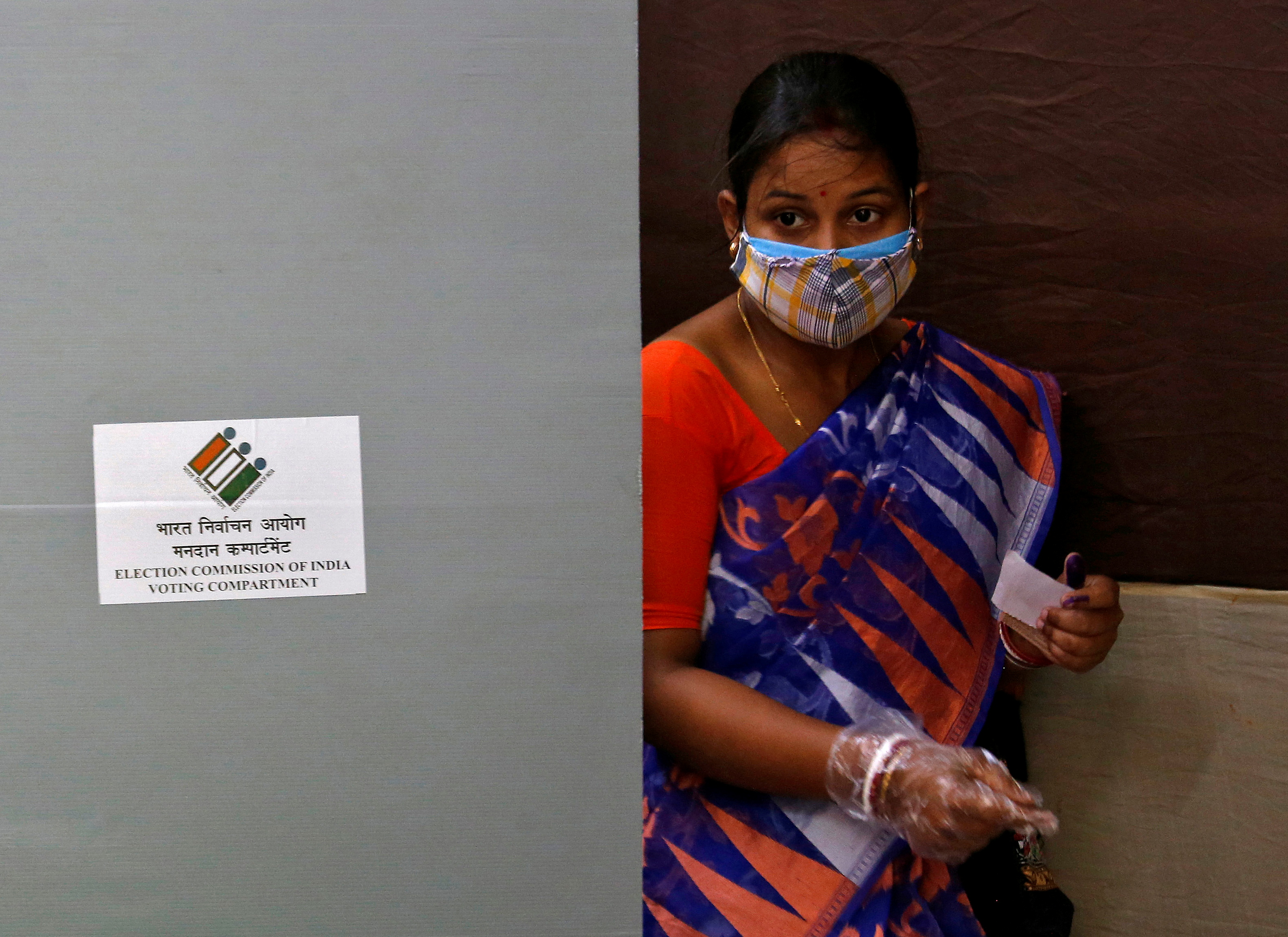 A woman wearing a protective face mask leaves after casting her vote at a polling station in Kolkata